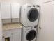 A modern laundry room featuring stacked washer and dryer with storage and countertop at 15028 Redcliff Dr, Tampa, FL 33625