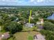 Aerial view of a home with a pool, a fenced yard, and mature trees nearby the lake at 18004 Clear Lake Dr, Lutz, FL 33548