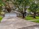 Charming home featuring a three-car garage, landscaped front yard, and mature trees that provide ample shade at 18004 Clear Lake Dr, Lutz, FL 33548