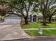 Charming home featuring a three-car garage, landscaped front yard, and mature trees that provide ample shade at 18004 Clear Lake Dr, Lutz, FL 33548