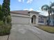 This home has an attached 2-car garage and an arched entryway, enhanced by mature landscaping at 18423 Meadow Blossom Ln, Tampa, FL 33647