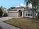 Charming home featuring an arched entryway, two car garage and lush palm tree at 18423 Meadow Blossom Ln, Tampa, FL 33647