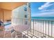 Balcony with table and chairs overlooking a white sand beach and ocean at 18610 Gulf Blvd # 607, Indian Shores, FL 33785
