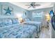 Bright bedroom features two beds with cool coastal themed decor and a ceiling fan at 18610 Gulf Blvd # 607, Indian Shores, FL 33785