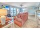 Open-concept living space with coral sofas, balcony access, and a view into the dining area and kitchen at 18610 Gulf Blvd # 607, Indian Shores, FL 33785