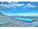 Beachfront pool with ocean views, lounge chairs, and brick pavers beneath a beautiful blue sky with picturesque clouds at 18610 Gulf Blvd # 607, Indian Shores, FL 33785