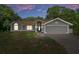 Charming single-story home featuring a two-car garage and landscaped front yard, set against a colorful sunset sky at 204 Oak Lake Dr, Spring Hill, FL 34608