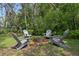 Cozy backyard firepit area with four gray Adirondack chairs in a tranquil setting at 204 Oak Lake Dr, Spring Hill, FL 34608