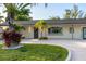 Charming home exterior showcasing a manicured lawn, tropical landscaping, and modern lighting fixtures at 243 45Th Ne Ave, St Petersburg, FL 33703