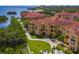 Beautiful waterfront building with manicured lawn, lush trees, and red tiled roof, with ocean views in the distance at 2724 Via Murano # 639, Clearwater, FL 33764