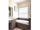 Bright bathroom featuring a large soaking tub, window, and vanity with decorative mirror at 3326 Acacia Bay Ave, Wesley Chapel, FL 33543