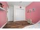 Bedroom featuring wood floors, an accent wall, closet with white doors and playful decor on the pink wall at 3326 Acacia Bay Ave, Wesley Chapel, FL 33543