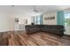 Living room boasting wood floors, a large sectional, natural light, and custom shelving, creating a cozy gathering space at 3326 Acacia Bay Ave, Wesley Chapel, FL 33543