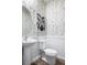 Stylish powder room with unique wallpaper, pedestal sink, and round mirror at 37225 Sagemoor Dr, Zephyrhills, FL 33541
