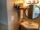 Vanity with a round mirror hanging above, towels, wooden shelf, and a cabinet below at 401 Pennsylvania Ave, Crystal Beach, FL 34681