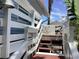 Exterior steps lead to a beautiful deck area with seating, surrounded by lush greenery and a blue sky at 401 Pennsylvania Ave, Crystal Beach, FL 34681