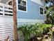 Exterior of the home with light-blue siding, tropical landscaping, and a partial view of the deck at 401 Pennsylvania Ave, Crystal Beach, FL 34681