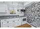 Cozy kitchen with white cabinets, gray granite countertops, and stylish wallpaper at 4202 Harbor House Dr # 24, Tampa, FL 33615