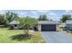 Single-story home featuring a well-manicured lawn, mature trees, and a two-car garage at 4228 Belle Isle Ct, New Port Richey, FL 34653