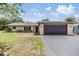 Charming single-story home with a well-manicured lawn, mature trees, and a two-car garage on a sunny day at 4228 Belle Isle Ct, New Port Richey, FL 34653