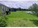 Expansive backyard featuring lush green lawn, mature trees, and tranquil pond views from screened-in porch at 5082 Inshore Landings Dr, Apollo Beach, FL 33572