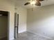A cozy bedroom featuring neutral walls, gray ceramic tile flooring, ceiling fan, and closet space at 5082 Inshore Landings Dr, Apollo Beach, FL 33572