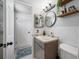 Well-lit bathroom with vanity, round mirror, decorative wall shelves and patterned rug at 5236 Madison St, New Port Richey, FL 34652