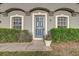 Close-up of a stylish front door with decorative trim, flanked by windows and manicured hedges at 5396 Berrien Ave, Spring Hill, FL 34608
