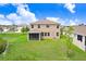 Aerial view of a home's backyard, featuring a screened-in porch, green lawn, and view of a nearby pond at 5430 Thistle Field Ct, Wesley Chapel, FL 33545
