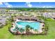 A full community pool, with beautiful palm trees, lounge seating, a covered area, and lush green grass at 5430 Thistle Field Ct, Wesley Chapel, FL 33545