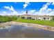 View of a home from across a pond, showcasing the backyard, neighboring houses, and community landscape at 5430 Thistle Field Ct, Wesley Chapel, FL 33545