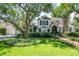 Inviting two-story home with lush green lawn, mature shade trees, brick walkway, detached garage, and charming curb appeal at 560 Bosphorous Ave, Tampa, FL 33606