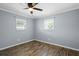 A bedroom featuring light gray walls, wood-look floors, two windows and a ceiling fan at 5860 99Th N Ave, Pinellas Park, FL 33782