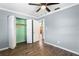 A bedroom featuring light gray walls, wood-look floors, and an open closet with a green back wall at 5860 99Th N Ave, Pinellas Park, FL 33782