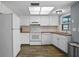 Bright kitchen featuring white cabinets and appliances, and a view of a backyard at 5860 99Th N Ave, Pinellas Park, FL 33782