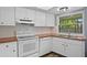 Bright kitchen featuring white cabinets and appliances, and a view of a backyard at 5860 99Th N Ave, Pinellas Park, FL 33782