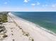 Expansive aerial view of a beach with blue water, white sand, and scattered vegetation at 615 Dream Island Pl # 210, Longboat Key, FL 34228