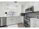 Bright kitchen features white cabinets, stainless steel appliances, and an eat-in bar area at 615 Dream Island Pl # 210, Longboat Key, FL 34228