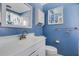 A blue bathroom features a vanity and sink, mirror, medicine cabinet, toilet and shower at 638 La Jolla Ave, Sun City Center, FL 33573