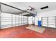 Spacious garage with a red floor and shelving, complete with an automatic door and a blue trash can at 638 La Jolla Ave, Sun City Center, FL 33573
