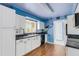 Kitchen features white cabinets, black appliances, colorful accent wall, and hardwood flooring at 638 La Jolla Ave, Sun City Center, FL 33573