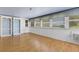 Spacious room with hardwood floors and built-in shelving, illuminated by natural light from large windows and a ceiling fan at 638 La Jolla Ave, Sun City Center, FL 33573