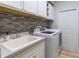Bright laundry room featuring white cabinetry, sleek sink, and modern washer and dryer, perfect for efficient home management at 7725 235Th E St, Myakka City, FL 34251