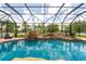 Sparkling pool with rock waterfall and surrounding greenery, all protected by a screened enclosure for endless outdoor fun at 7725 235Th E St, Myakka City, FL 34251