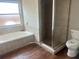 Bright bathroom with a soaking tub, tiled shower, wood-look floors, and a modern toilet at 8033 55Th E St, Palmetto, FL 34221
