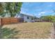 Large grassy backyard with a wooden fence, mature trees, and a partial view of the home's exterior at 832 Birdie Way, Apollo Beach, FL 33572