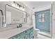 Stylish bathroom features striking blue tiled shower and a vanity with a marble countertop at 832 Birdie Way, Apollo Beach, FL 33572