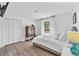 Bright bedroom features a wooden floor, white walls, and a large window with sheer curtains at 832 Birdie Way, Apollo Beach, FL 33572