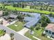 Aerial view of a single-story home with manicured lawn, lush landscaping, and water view at 832 Birdie Way, Apollo Beach, FL 33572