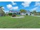 Landscaped home featuring lush green lawn, stone garden, mature trees, and charming curb appeal at 832 Birdie Way, Apollo Beach, FL 33572